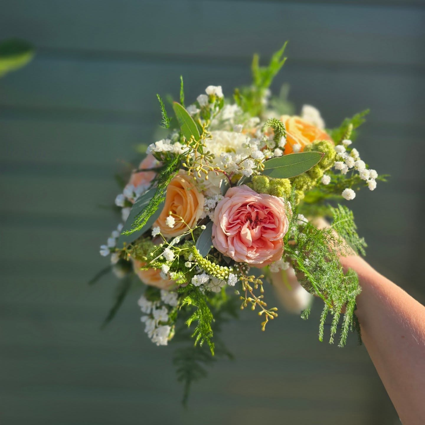 Buket fra Den lille blomsterbod med rosa og abrikosfarvede roser, hvide blomster og grønt