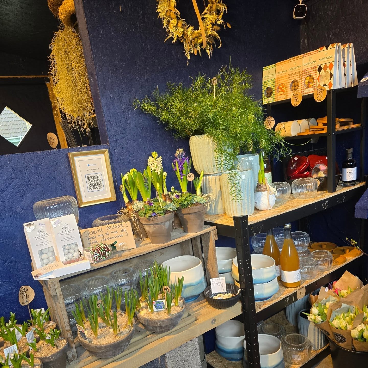 Hylder med tilplantninger, vaser og små gaver i blomsterboden
